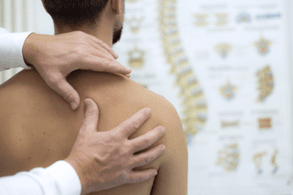 Dr. testing man's upper shoulders and neck.