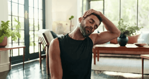 Man sitting face too stretching his neck to the left aided by his left hand.