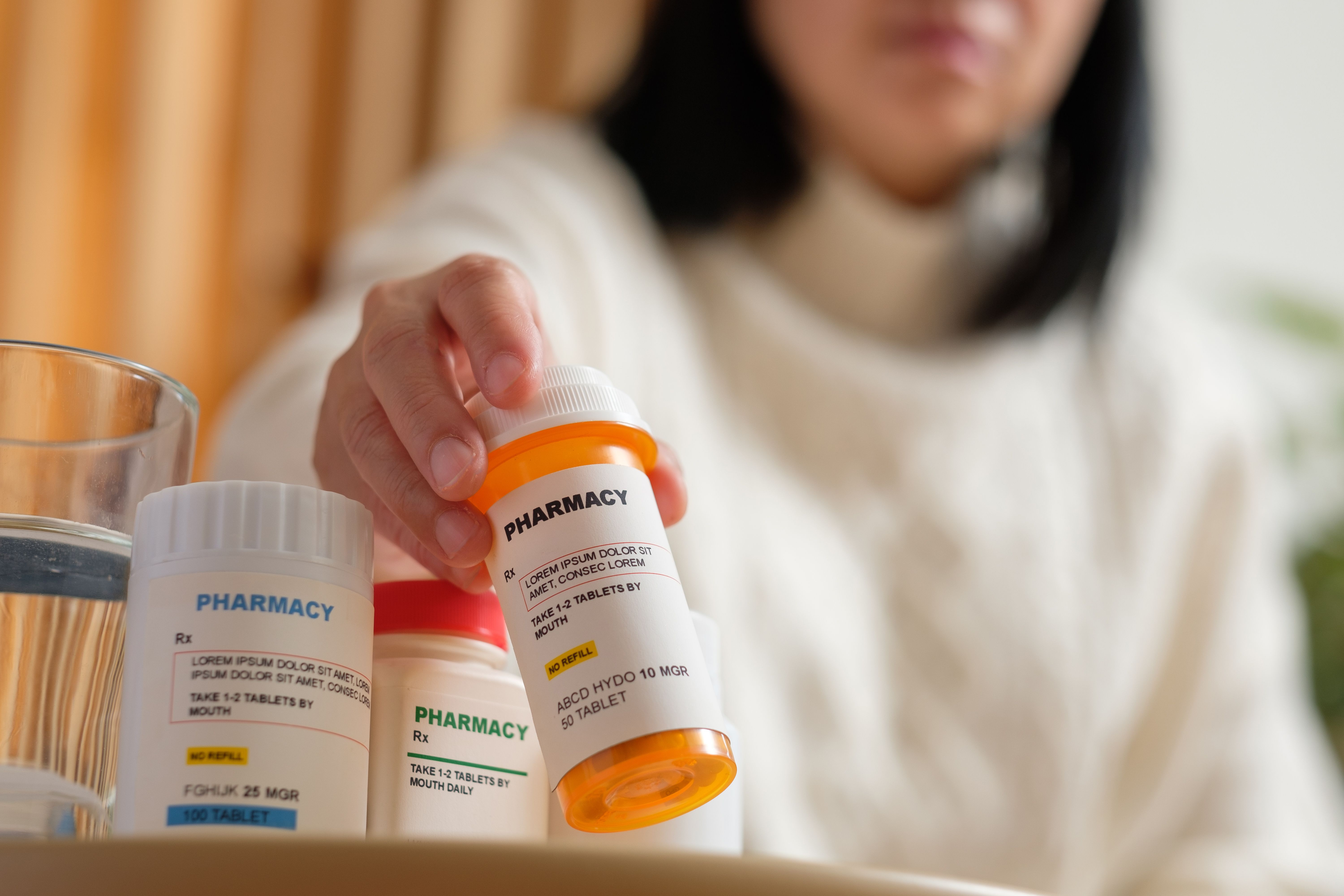 A woman with a neck brace holds a bottle of prescription pain medication, highlighting the use of pharmacological treatments for managing chronic back and neck pain.